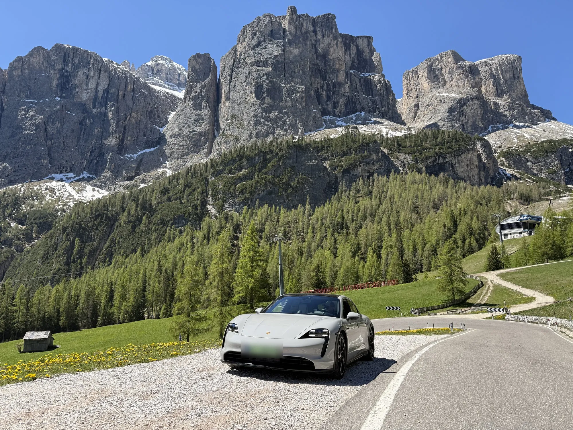Porsche Taycan Cross Turismo on a hairpin below the Sella group, Passo Gardena, Dolomites
